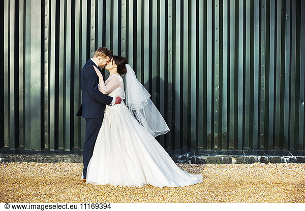 A bride and bridegroom on their wedding day  kissing each other.
