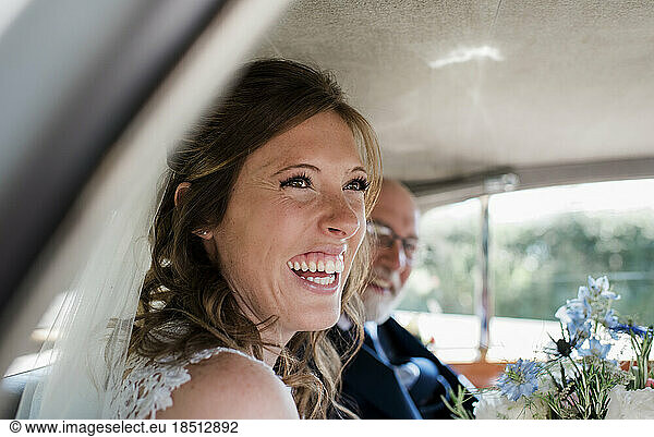 a bride laughing in her car on her wedding day