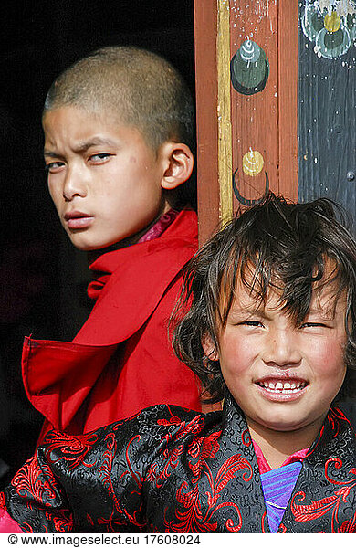 A brother and sister stand near a doorway outside a building in Bhutan; Paro  Bhutan