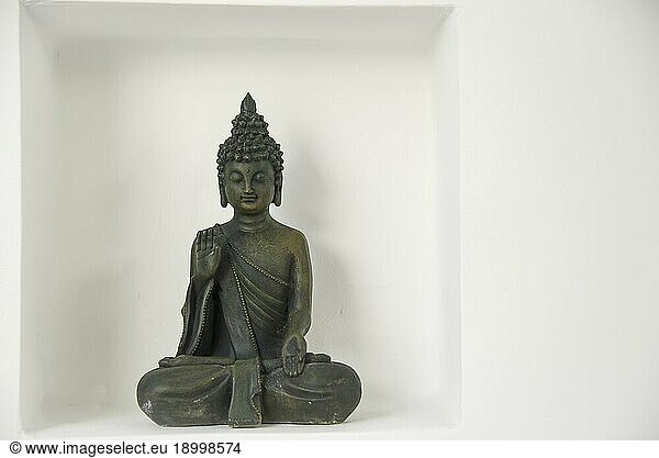 A buddha figure with in a recession on a white wall