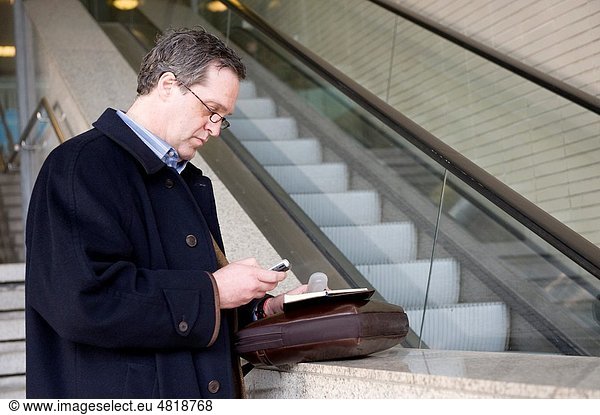 A buisinessman is looking at his messages while consulting his planner