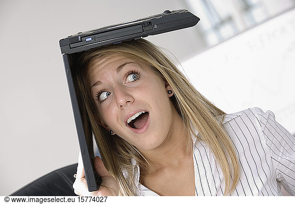 A business woman with a laptop over her head.
