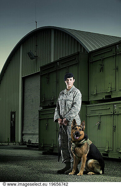 A Caucasian  female Air Force Security Forces Airman in uniform gives her military working dog a command sit.