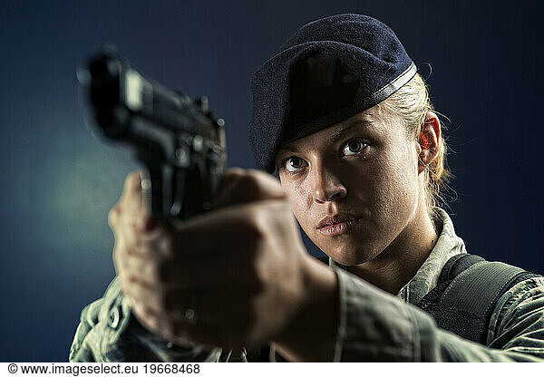 A Caucasian  female  Air Force Security Forces Airman in uniform poses with her M-9 pistol.
