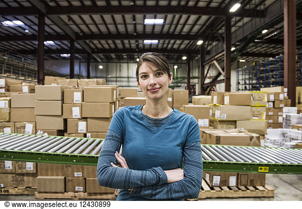 A Caucasian female warehouse worker in a distribution warehouse.