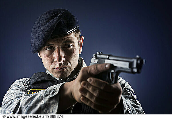 A Caucasian  male  Air Force Security Forces Airman in uniform poses with his M-9 pistol.