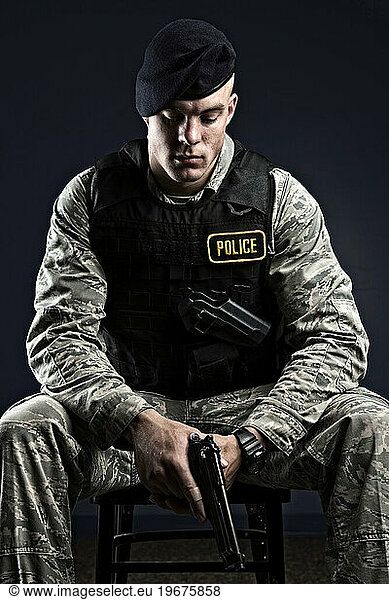 A Caucasian  male  Air Force Security Forces Airman in uniform poses with his M-9 pistol.