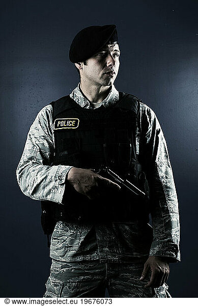 A Caucasian  male  Air Force Security Forces Airman in uniform poses with his M-9 pistol.