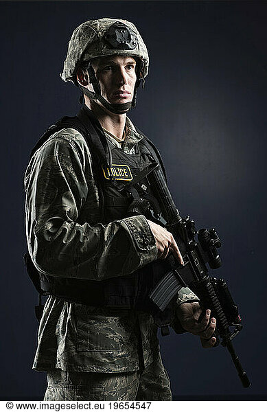 A Caucasian  male  Air Force Security Forces Airman in uniform poses with his M-4 rifle.