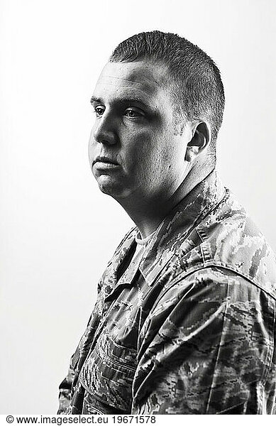 A Caucasian  male  Air Force Security Forces Airman in uniform sits for a profile black and white portrait with a white backdrop.