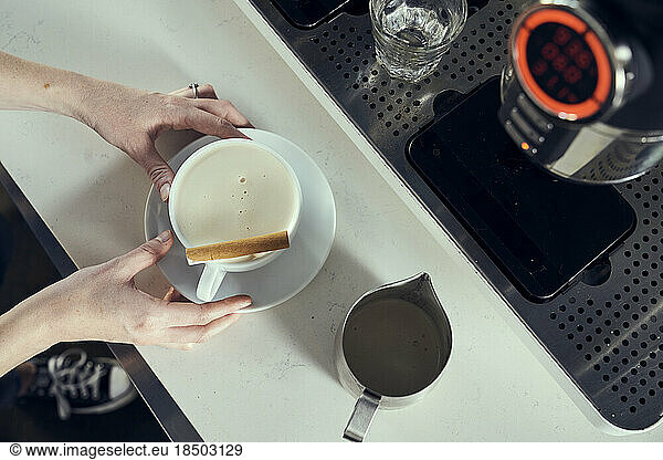 A chai latte is finished with a cinnamon stick garnish.