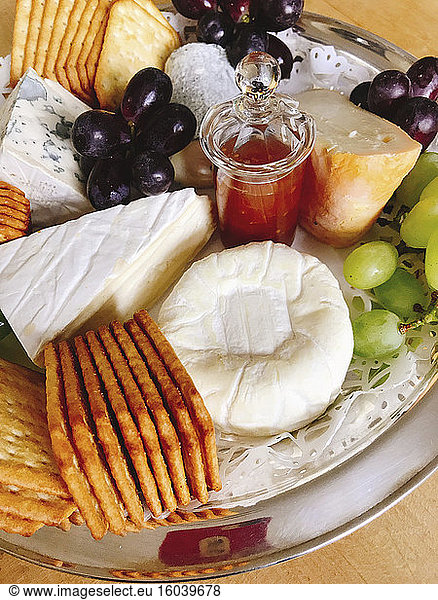 A cheese platter with crackers and grapes