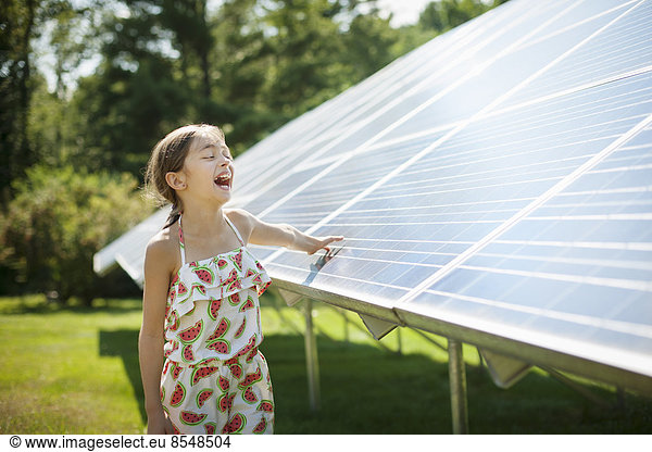 A child in the fresh open air on a sunny day,  beside solar panels at a farm in New York State,  USA.
