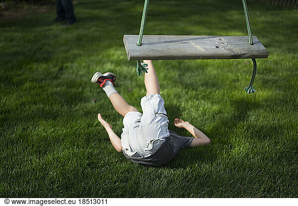 A child lays on the ground after falling from a wooden swing