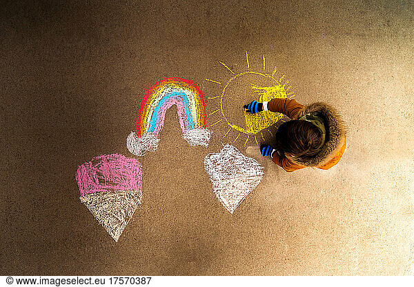 a child making artwork with chalk on a sidewalk