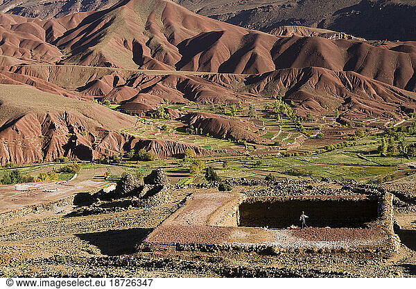 A child plays on a farm roof in Tasgaiwalt in the lush Tessaout Valley  M'Goun Massif  Central High Atlas  Morocco.
