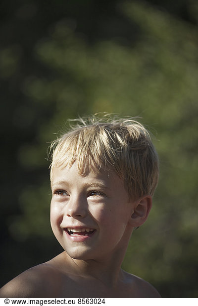 A child turning his head to look over his shoulders  smiling.