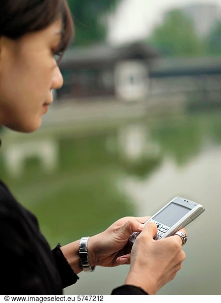 A Chinese businesswoman taps away on her PDA smart phone.