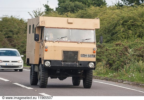 A classic MOD vehicle driving on a main road in the Uk.