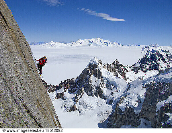A climber climbs the steep north face of Torre Egger  with the peaks of Cerro Rincon below  and the glaciers of the Southern Pa