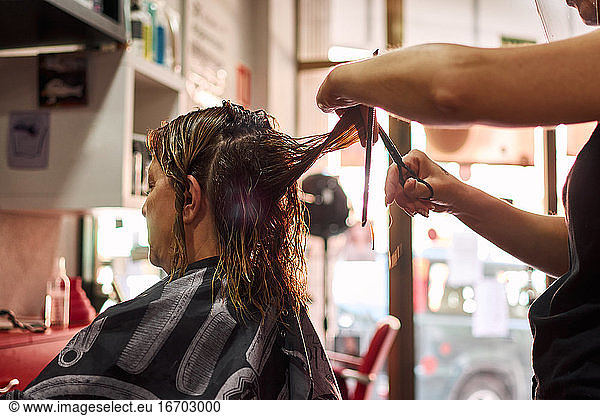 A close-up of a hairdresser cutting client's hair. Small business