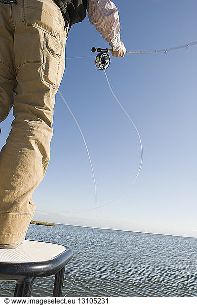 A closeup of a fly fisherman casting for redfish and tarpon in the marsh