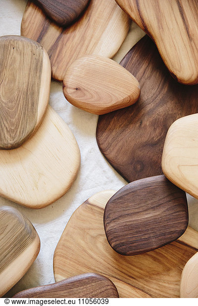 A collection of small smooth turned wooden objects of different colours and wood grain patterns.