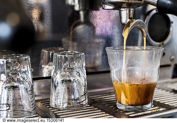 A commercial expresso machine in a coffee shop making an expresso shot.