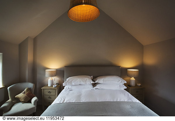 A cosy bedroom decorated in neutral colours  with a double bed and bedside lights on. Hospitality.