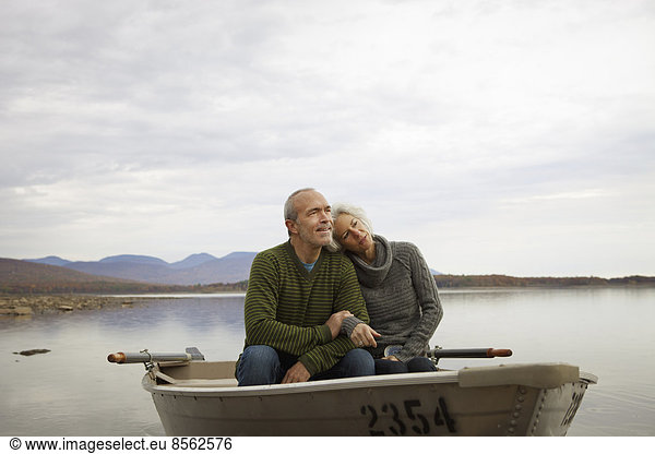 A couple, man and woman sitting in a rowing boat on the water on an autumn day.