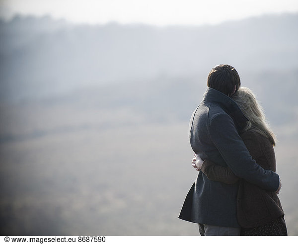 A couple embracing. Standing in a field in the country.