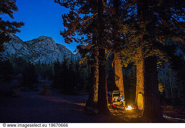 A couple hang out around a fire with their pickup truck while camping near Sonora Pass  CA.