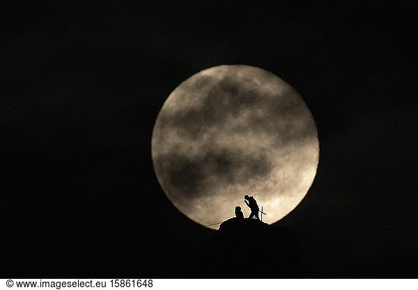 A couple of climbers setting a rope with full moon in the background