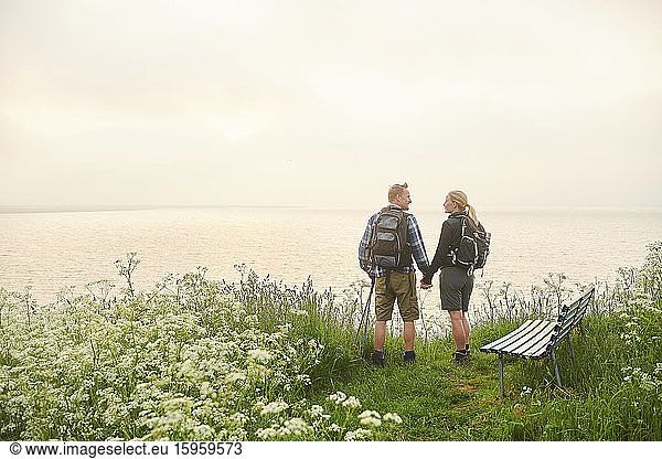 A couple on a coastal hiking path  standing looking over the sea