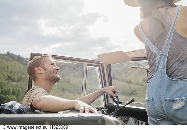 A couple on a road trip in an open top jeep.