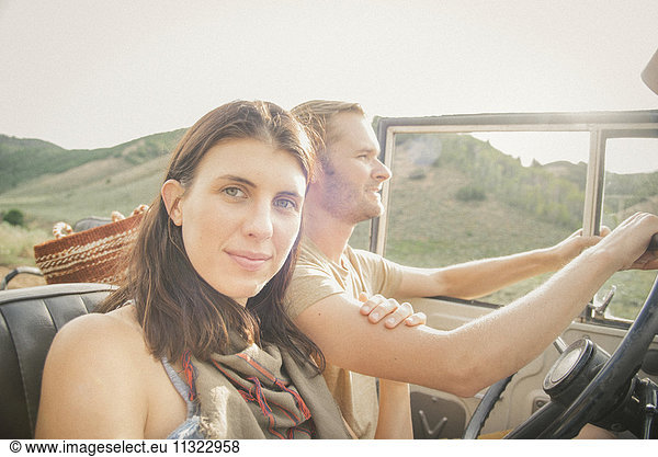 A couple on a road trip in the mountains side by side in a jeep.
