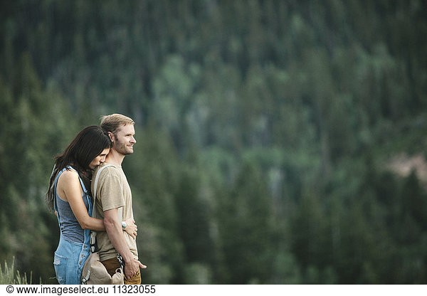 A couple standing embracing in the mountain landscape.