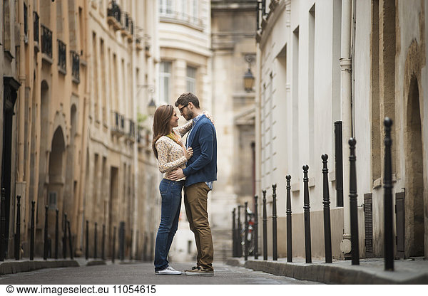 A couple standing gazing at each other  in a narrow street in a city.