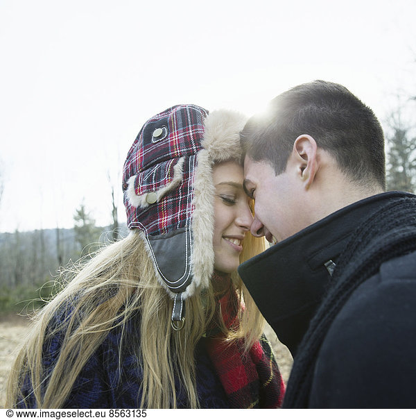 A couple  young man and woman  face to face embracing  outdoors on a cold winter day.