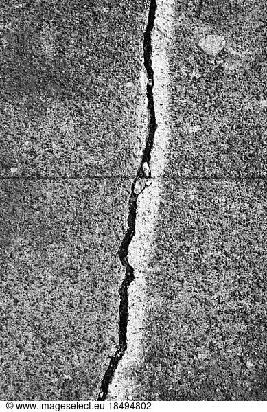 A crack between flagstones painted with a white line  on a concrete sidewalk surface.