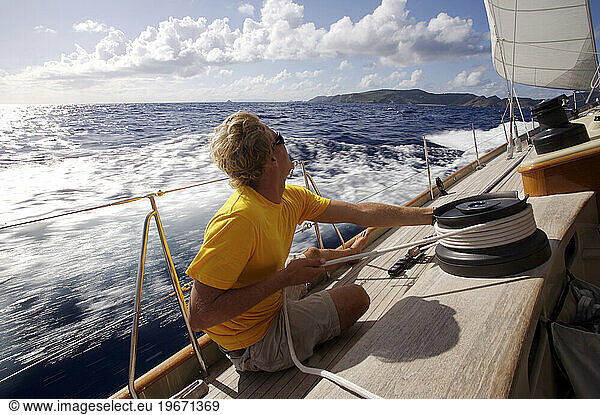 A crewmate tightens a line while onboard a sail boat near St. Bartholomew  French West Indies.