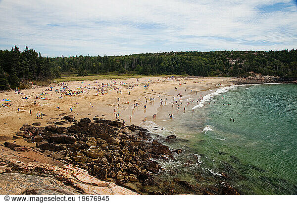 A crowded beach on a party cloudy afternoon.