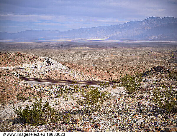A curvy desert highway leads to a valley in the desert.
