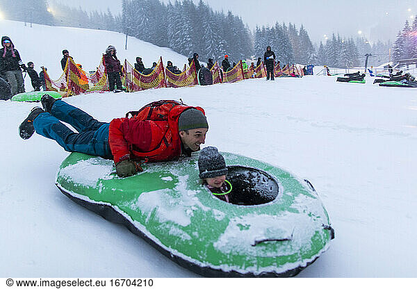 A dad rides with his daughter in a tube down a snowhill in Oregon.