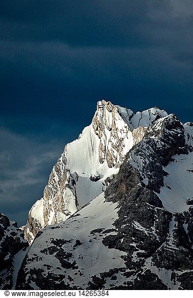 A dark cloudy sky contrasting with a snow-capped peak in the Dolomites of Belluno  Cadore  Veneto  Italy Europe
