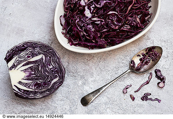 A dish of cooked red cabbage and half a raw cabbage.