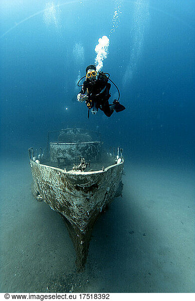 A diver stands on an old wreck.