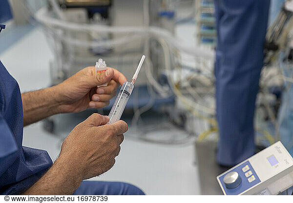 a doctor prepares a syringe during surgery