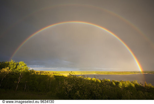 A double rainbow in the sky arching over the land.