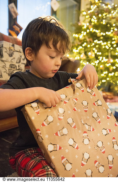 A family at home on Christmas Day. A boy unwrapping a large present.